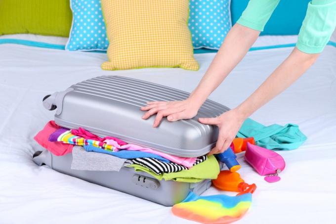Dziewczynka zbiera walizkę na łóżku bliska