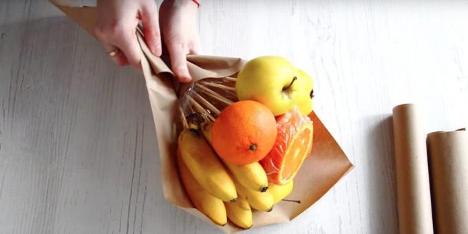 Umieścić kilka owoców z rękami w poprzek papieru i owinąć spód
